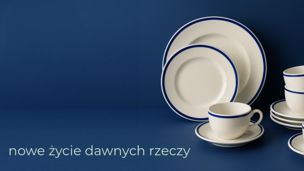 Kompozycja porcelanowej zastawy stołowej (talerze, filiżanki ze spodkami) w kolorze białym z cienkim, granatowym obrzeżem, ustawiona na gładkim, granatowym tle. Na dole, po lewej stronie, widoczny jest napis "nowe życie dawnych rzeczy".